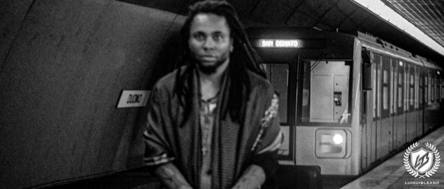 Black-and-white photograph of Luigui Bleand standing on a platform of the Duomo metro station in Milan, a train showing the destination San Donato behind him